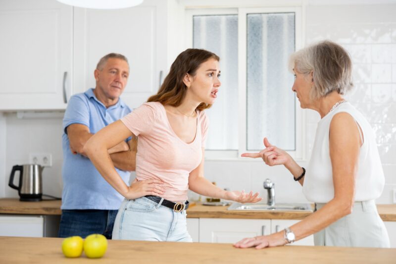 Young woman arguing with an older couple in a kitchen