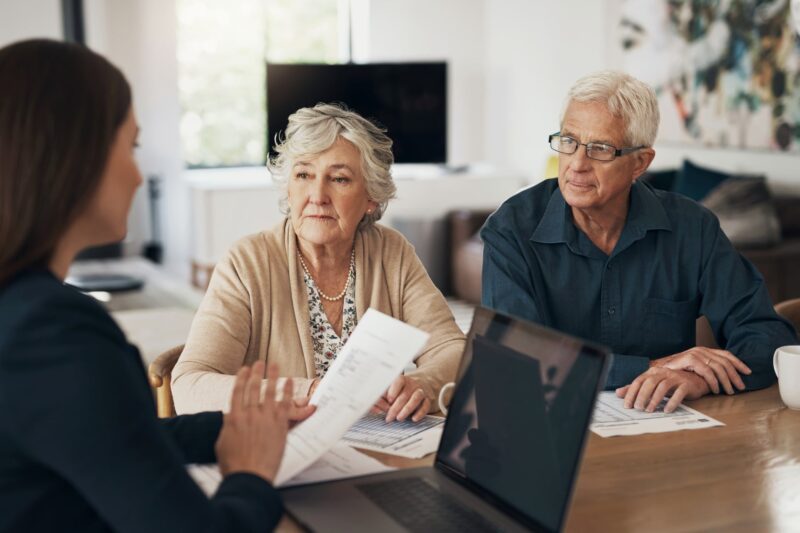 Two older adults and a younger woman reviewing a document together at a table
