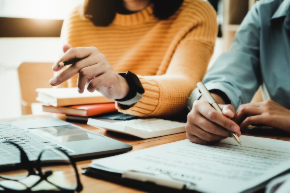 Two people reviewing documents at a table, one taking notes