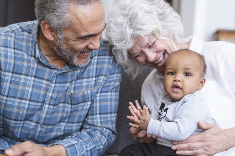 Grandparents and a grandchild seated together, smiling at the camera