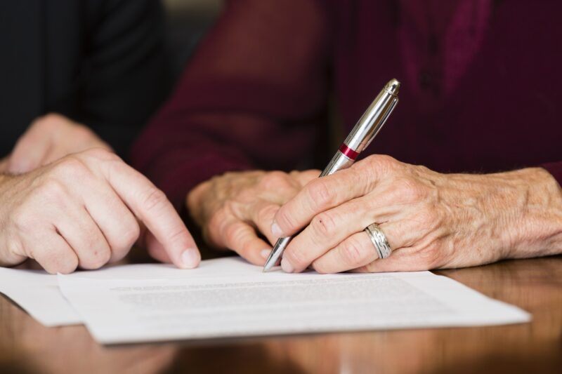 Elderly hands holding a pen, signing a document