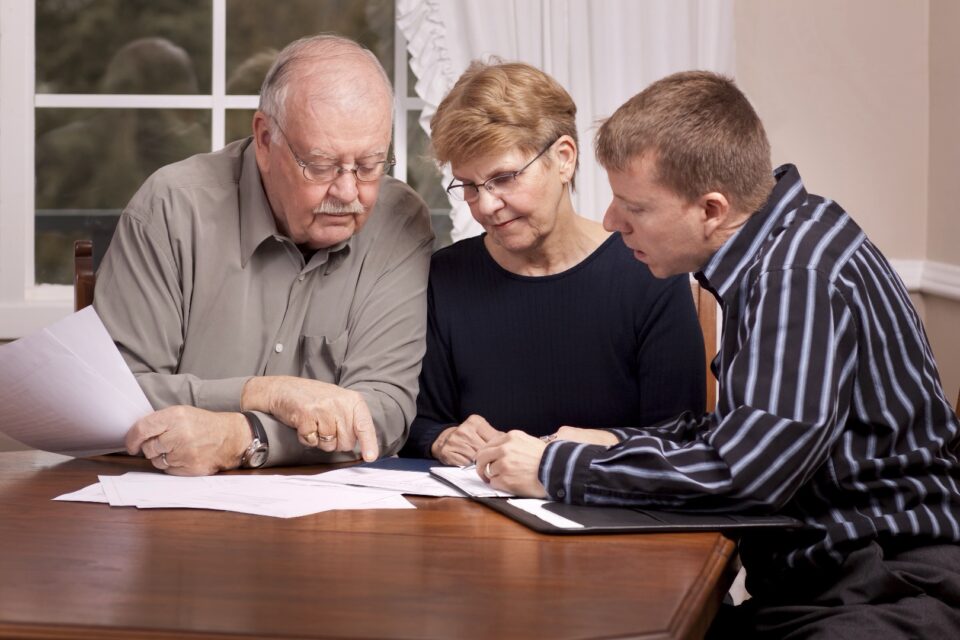 Older man and boy sitting at a table reviewing documents together