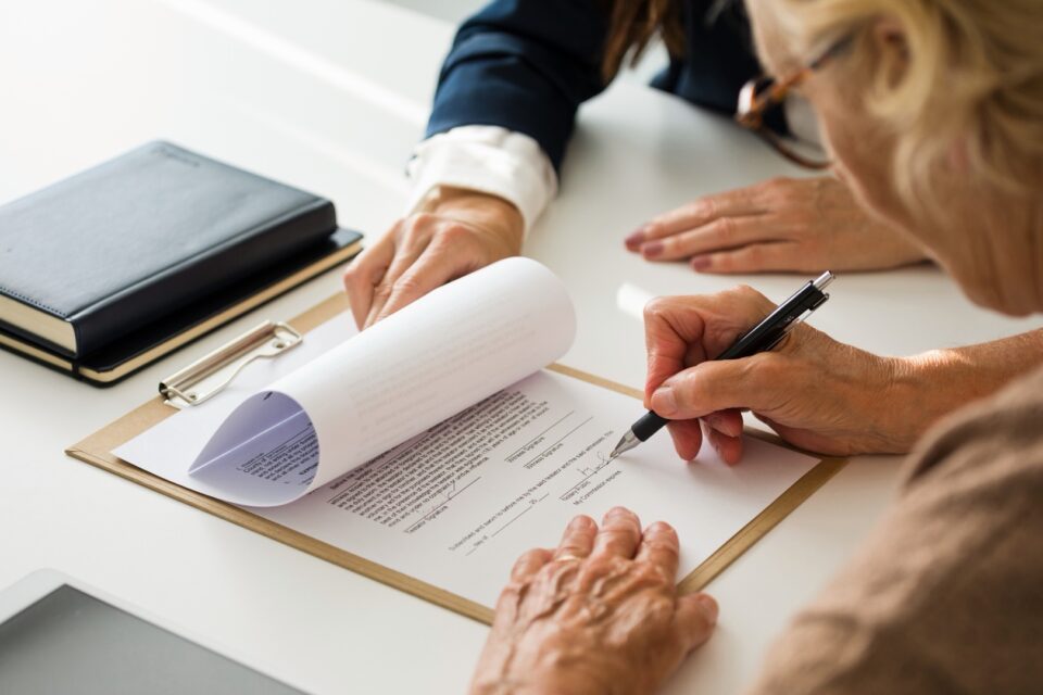Two people leaning over blueprints or plans at a desk with a pen