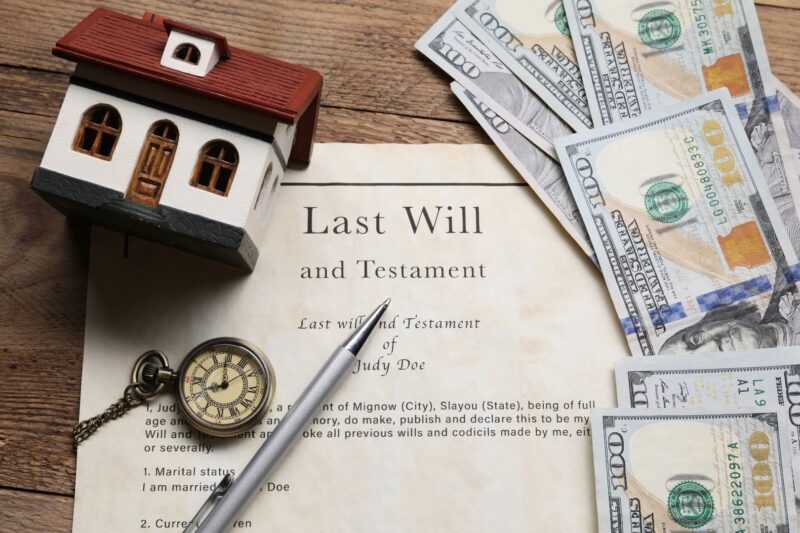 Last Will and Testament document with a pocket watch, money, and a house figurine
