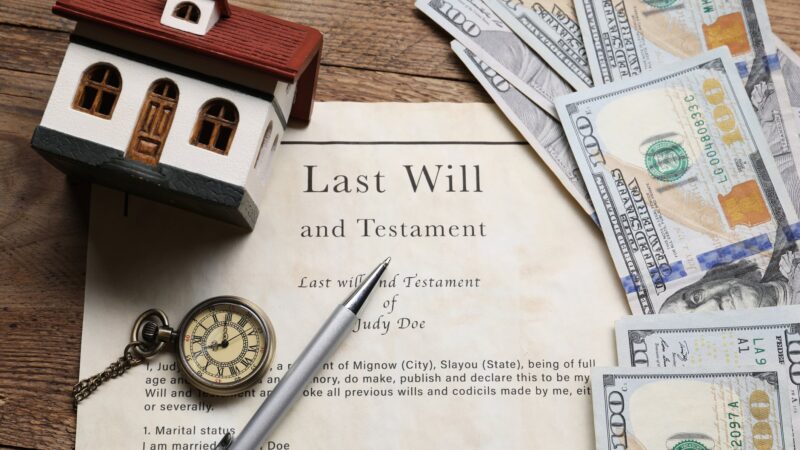 Last Will and Testament document on a table with a pocket watch and scattered cash