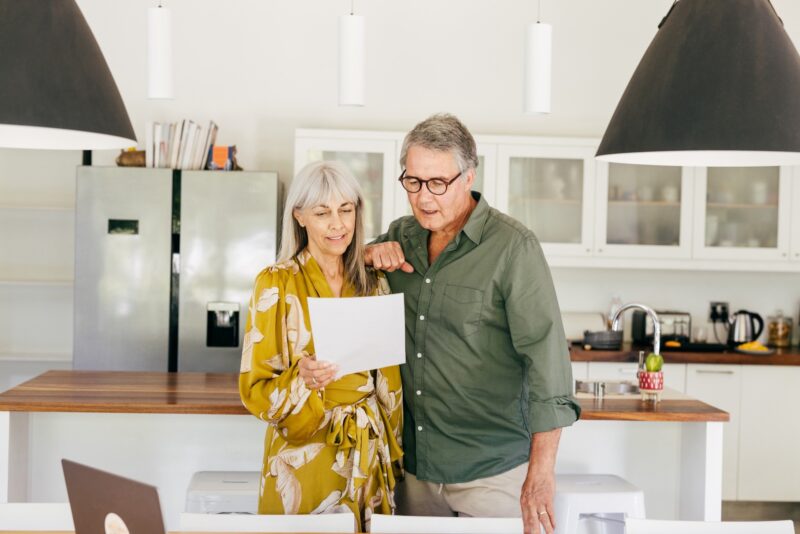Couple standing together holding a document in a bright modern kitchen
