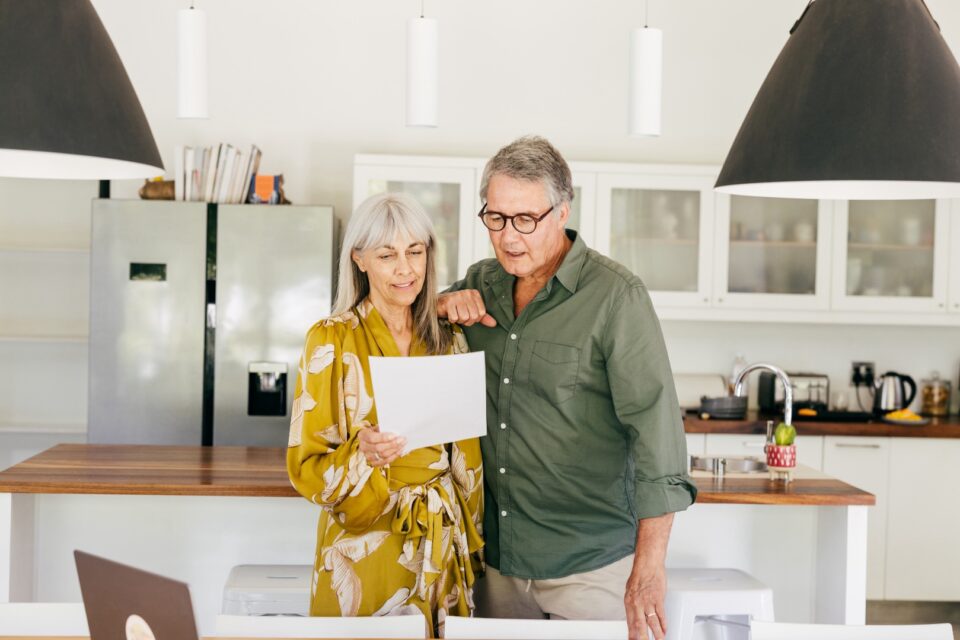 Couple standing together holding a document in a bright modern kitchen