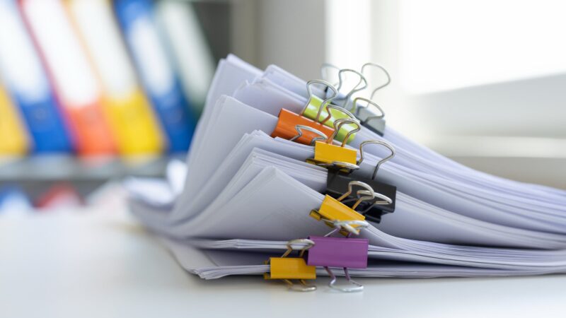 Stack of colorful binders and folders clipped together with binder clips