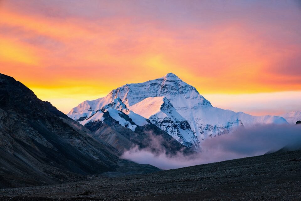 Mountain peak at sunset with dramatic orange and pink sky and clouds